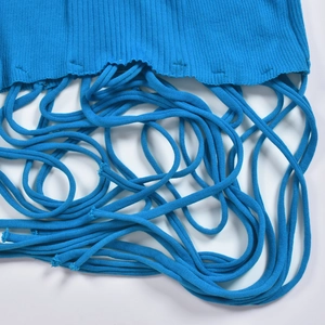 Détail de la maille côtelée bleue et des longues franges sur l'ourlet de la robe