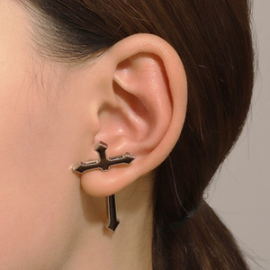 Detail showing a silver cross ear cuff earring worn on a model's left ear cartilage