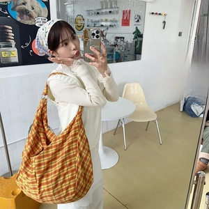 Detail of yellow and orange plaid tote bag in a casual hobo style fashion setting