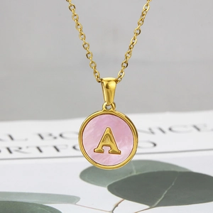 Macro shot of circular pink shell pendant with gold letter A on stainless steel chain