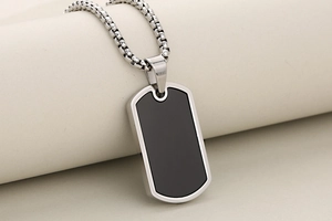 Close-up of a silver stainless steel dog tag necklace with a black inlay and bead chain