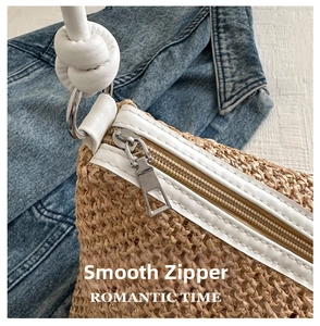 Detail of smooth metal zipper and white leather handle on natural woven straw bag