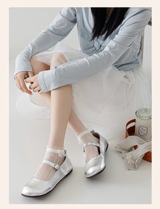 Close-up of silver Mary Jane flat shoes with buckle strap and metallic textured finish