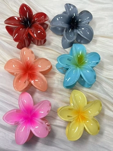 Flat lay of six colorful orchid flower hair claws in resin on white silk background