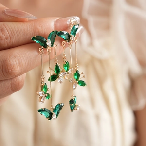 Vue détaillée de longues boucles d'oreilles papillon dorées avec pierres précieuses