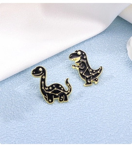 Détail de deux épingles dinosaures en émail noir avec constellations dorées