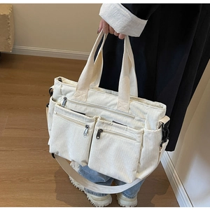 Detail of white corduroy tote bag with dual front zipper pockets and adjustable strap