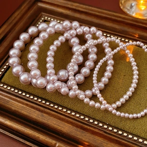 Detail of pink pearl bracelet set on green velvet padding in a vintage frame