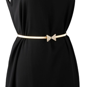 Ceinture extensible dorée avec nœud en strass portée sur une robe noire