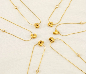 Macro detail of golden bubble initial necklaces with sparkling zircon stone accents