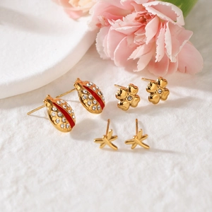 Close-up of gold insect stud earrings set with red enamel ladybug and floral motifs