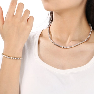 Détail d'un ensemble collier et bracelet tennis en acier doré serti de zircons brillants