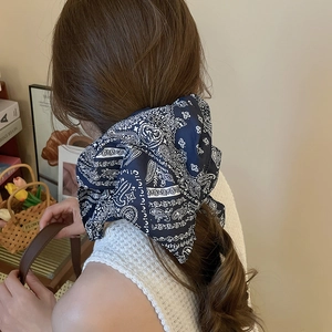 Détail d'un chouchou à nœud motif paisley bleu et blanc porté en queue de cheval