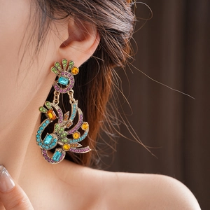 Detailed close-up of a vintage peacock earring with colorful rhinestones on a golden base