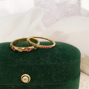 Detail van 18k gouden ringen met sterzetting en regenboogzirkonia op fluwelen doos