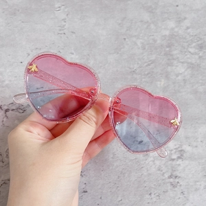 Close-up of heart-shaped glitter sunglasses with pink-blue gradient lenses and bee accent