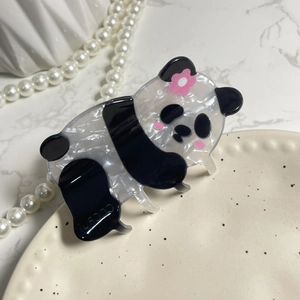 Cute panda-shaped acetate hair claw clip with pink flower on white ceramic plate