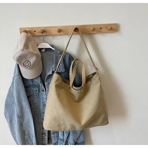 Detail of khaki canvas tote bag hanging on a hook with denim jacket for casual daily outfit