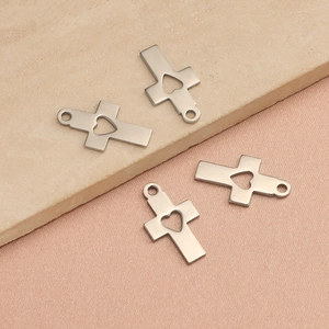 Gros plan de quatre pendentifs croix en acier inoxydable avec découpes en forme de cœur