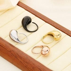 Detailed view of teardrop shaped stainless steel rings in four colors on a velvet tray