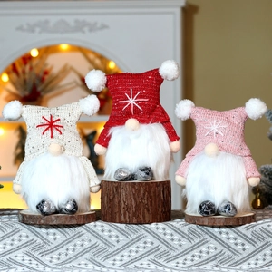 Three glowing Christmas gnomes in white, red and pink on wooden bases with warm lights