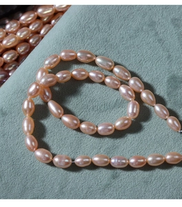 Macro shot of 5-6mm pale pink oval freshwater pearls with high luster on green fabric
