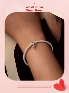 Detailed close-up of a silver braided bracelet featuring a two-tone heart clasp and pendant