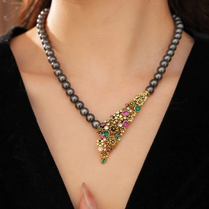 Gros plan du collier fleur vintage avec perles gris foncé et strass colorés sur un mannequin