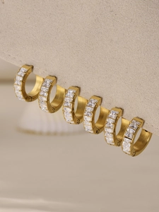 Macro shot of gold-plated hoop earrings featuring square-cut sparkling zircon stones