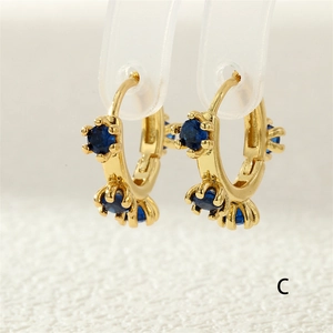 Golden hinged hoop earrings with three prong-set blue zircons in a classic round cut