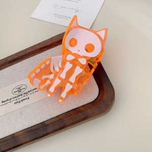 Close-up of a translucent orange acrylic cat skull hair claw clip for Halloween