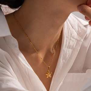 Close-up of elegant gold starfish pendant necklace worn by a model for resort style
