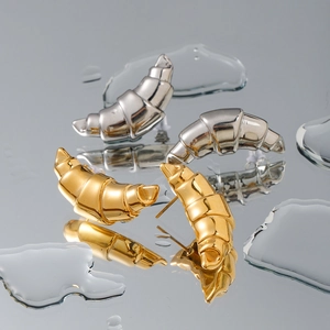 Polished 18k gold and silver croissant dome stud earrings on a mirrored background