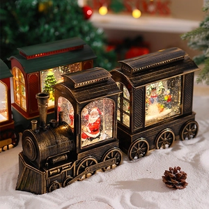 Close-up of vintage bronze Santa train music box with glowing snow globe and festive lights
