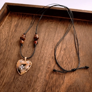 Macro detail of amber heart pendant with gold edge and vintage star ornaments on wood