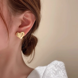 Élégantes boucles d'oreilles cœur dorées avec tiges en argent 925 portées par un modèle