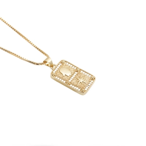 Detail of a gold Hamsa Hand and star pendant inlaid with clear zircon on a box chain
