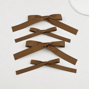 Close-up of four brown ribbon hair bows in two sizes with smooth satin texture