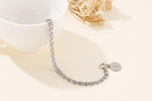 Detail view of silver double-layered chain bracelet with queen coin pendant and dry flowers