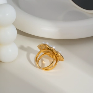 Close-up of golden shell ring with small pearls on white surface for elegant style