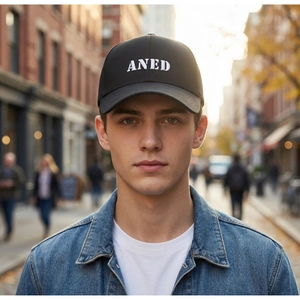 Close-up of black baseball cap with white ANED 3D embroidery worn in street style