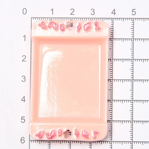 Miniature pink dollhouse tray with polka dot patterns on a centimeter scale grid mat