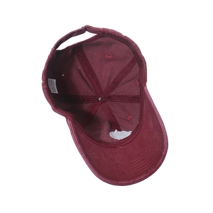Detailed macro view of 100% cotton wash label and metal buckle on dark red baseball cap