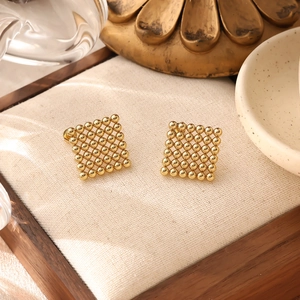 Minimalist square heart earrings in 18K gold plated steel on a beige jewelry tray