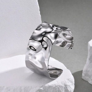 Close-up of a wide silver stainless steel cuff bracelet with irregular hammered texture