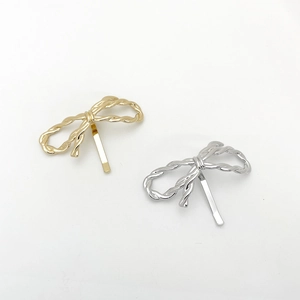 Detail of minimalist gold and silver alloy bow hair clips with elegant metal texture
