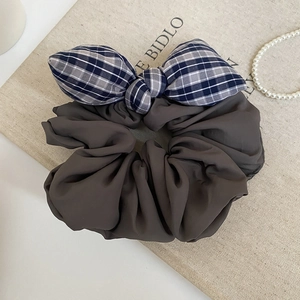 Close-up of a vintage dark taupe scrunchie with a blue-grey plaid bow hair accessory