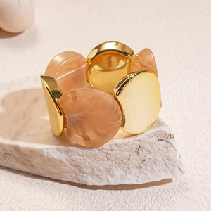 Dettaglio di bracciale elastico con dischi dorati e perline in resina marmorizzata