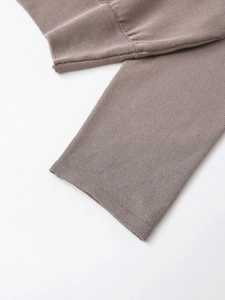 Détail rapproché de la manche d'un pull en maille marron montrant la texture douce