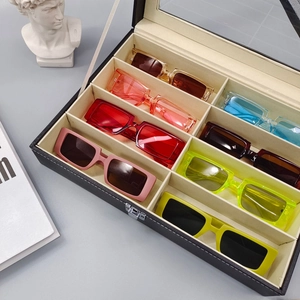 Plusieurs lunettes de soleil rectangulaires colorées dans un coffret de rangement noir